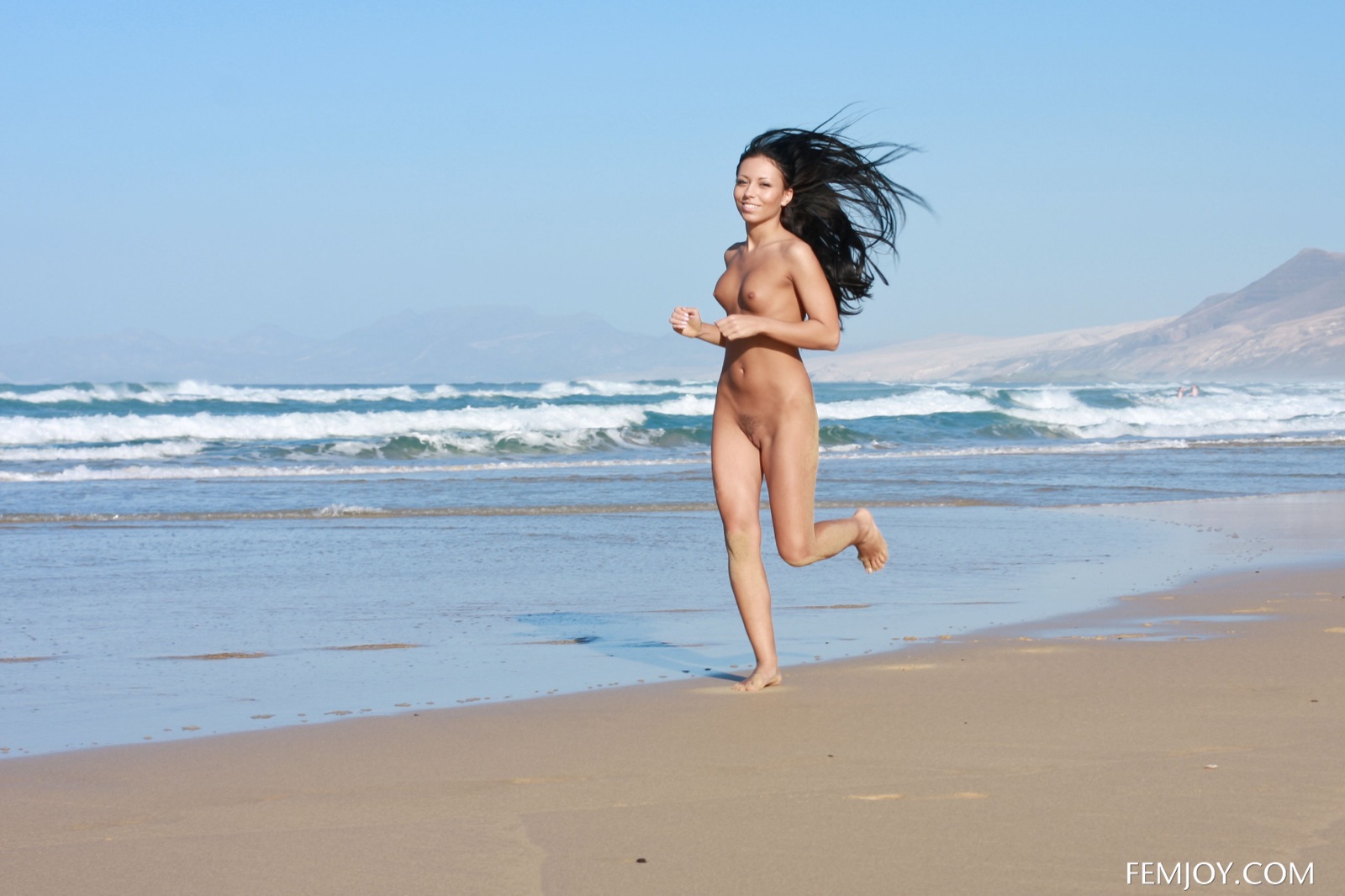 Стройняшка с волнистыми волосами до талии голая бегает по пляжу