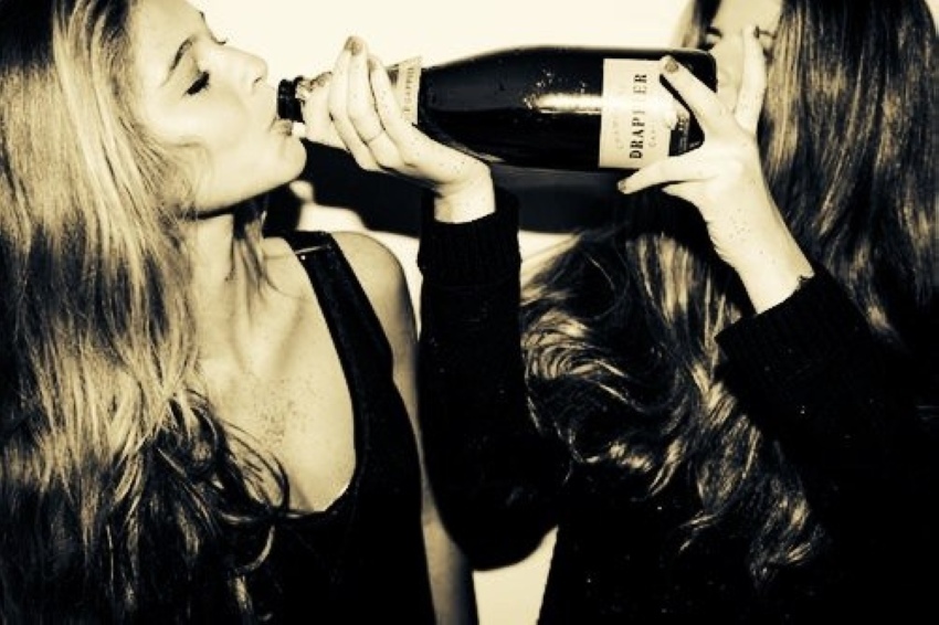 Две девушки с татуировками пьют шампанское