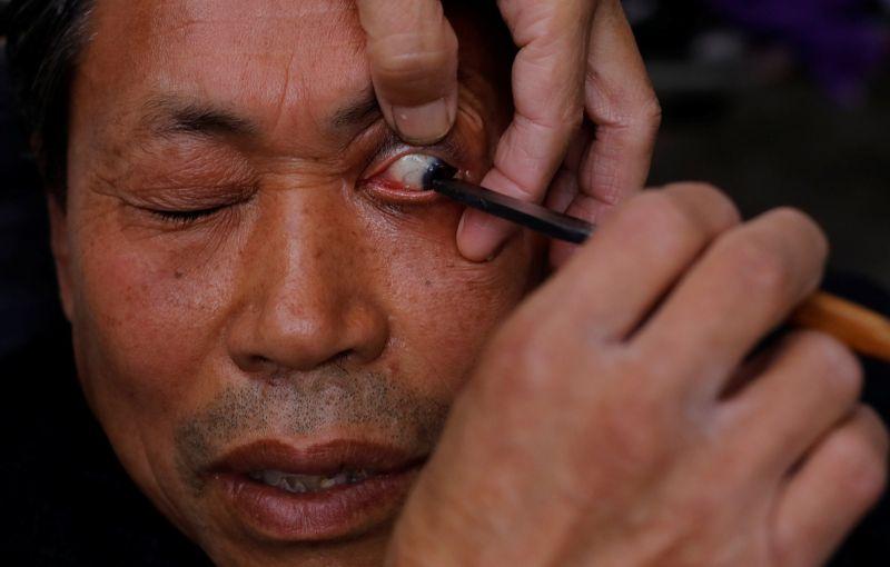 Китайский уличный парикмахер чистит глаза клиентов опасной бритвой