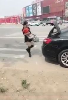 Молодая мамочка закрывает багажник машины ногой