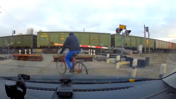 Рисковый велосипедист переезжает через железнодорожный переезд